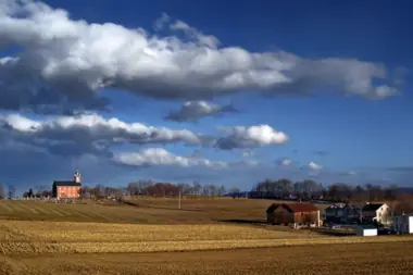 Open fields, farm buildings, and broad clouds in Falls Township.