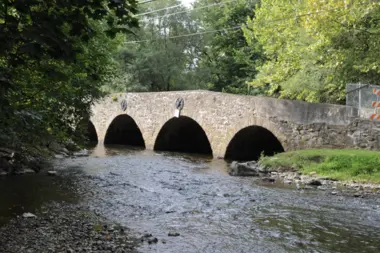A low stone bridge crossing a wooded Bucks County stream.